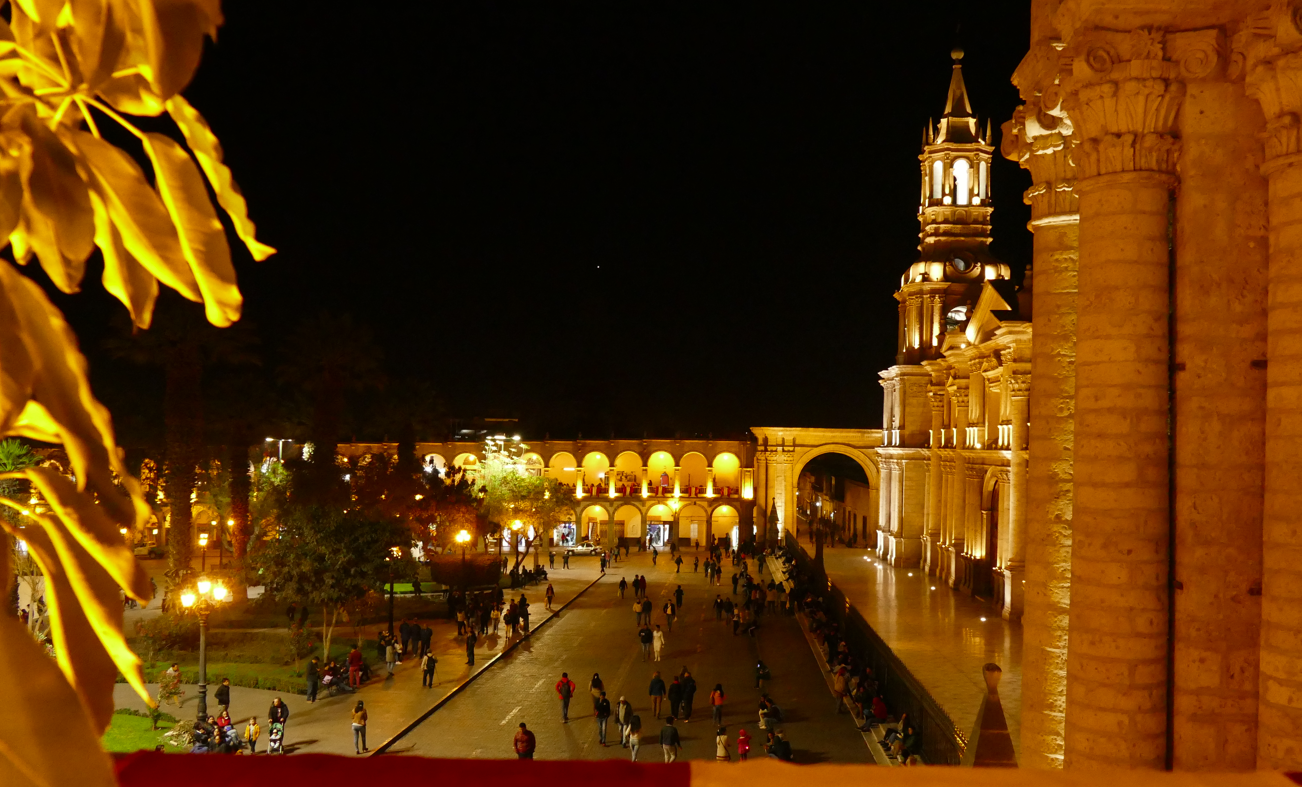 Nachtzicht op het Wapenplein in Arequipa, Peru. Verlichte kathedraal, wandelende mensen en zuilengalerijen.