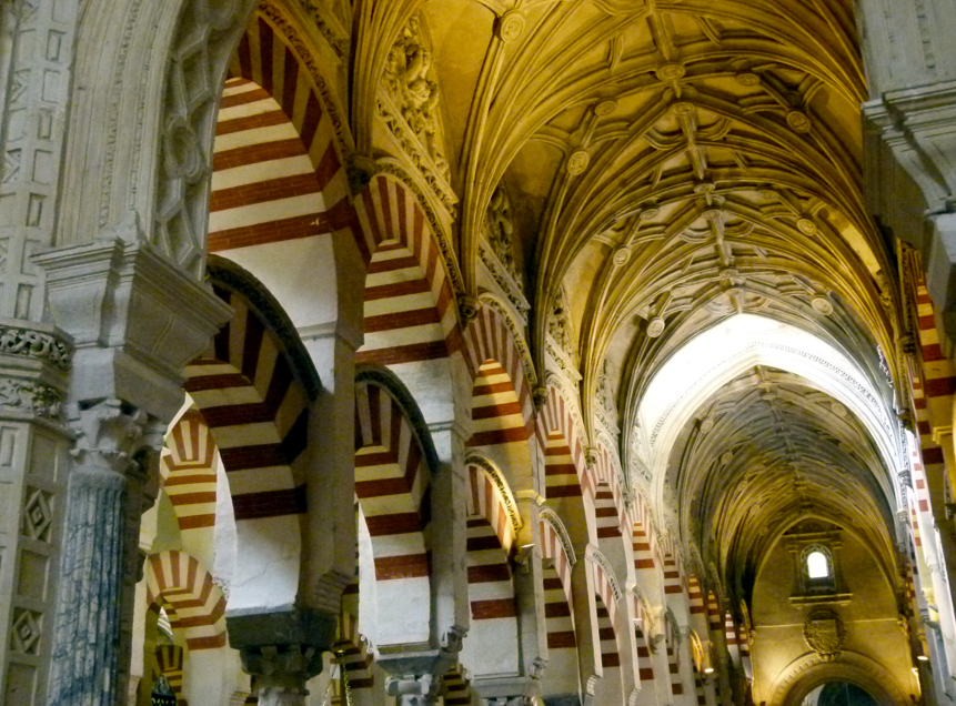 Interieur van de Mezquita-kathedraal in Córdoba, Spanje. Een reeks rood-wit gestreepte bogen die naar het plafond leiden.
