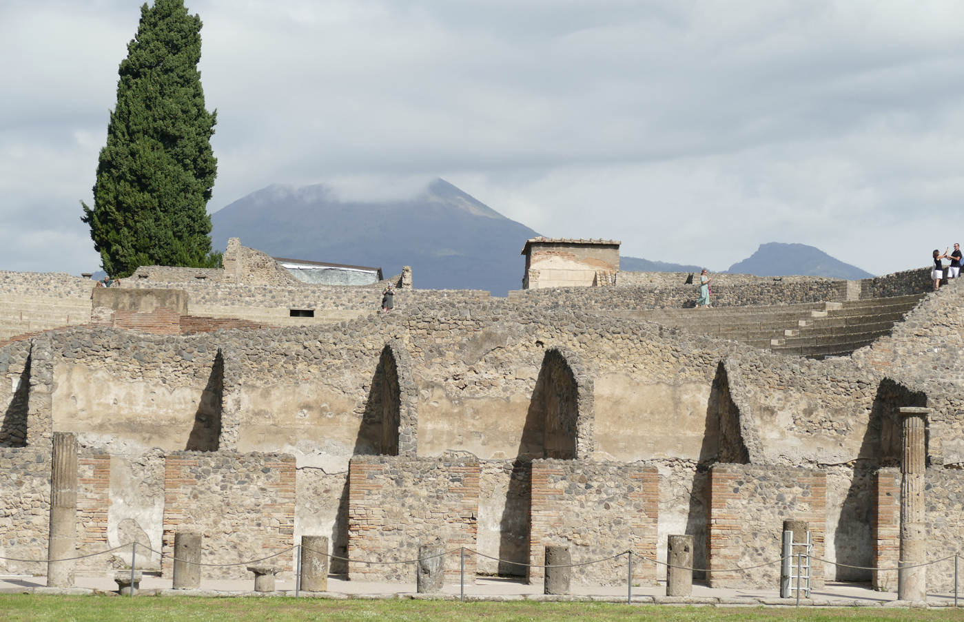 Ruïnes van het amfitheater van Pompeii, met de Vesuvius op de achtergrond op een bewolkte dag.