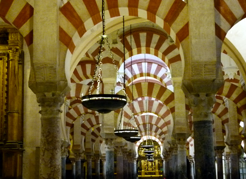 Interieur van de Grote Moskee van Córdoba. Zuilen met rood-wit gestreepte bogen, hangende lampen.