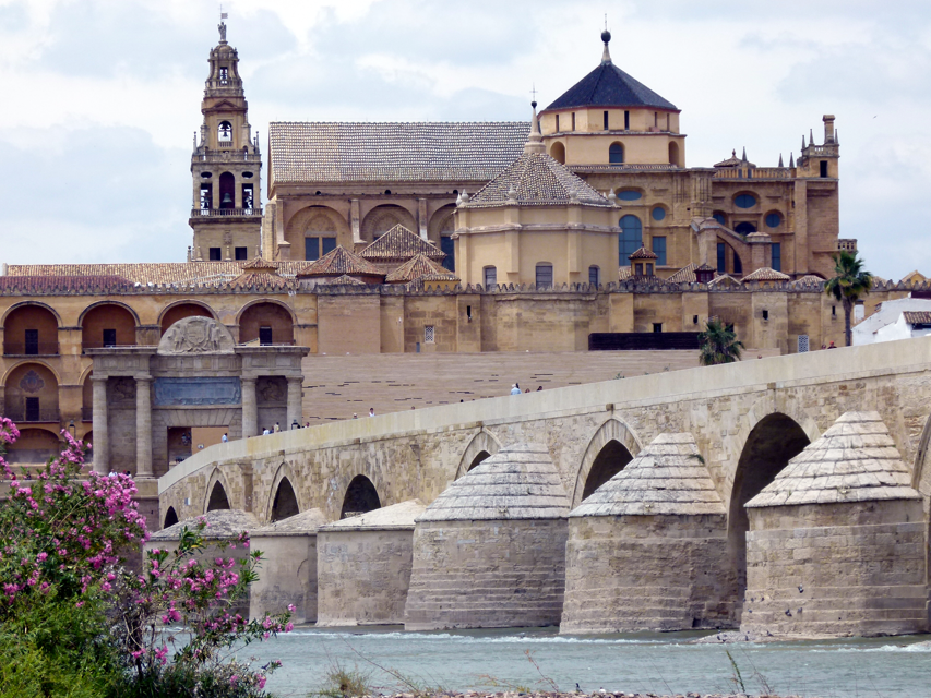 Romeinse brug en kathedraal in Córdoba, Spanje, beige stenen bouwwerken tegen een blauwe hemel.