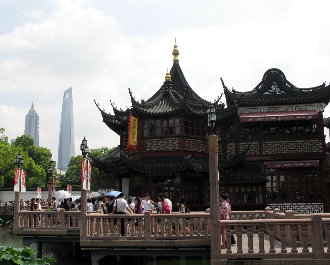Traditionele Chinese architectuur met een brug en de moderne skyline van de stad op de achtergrond.