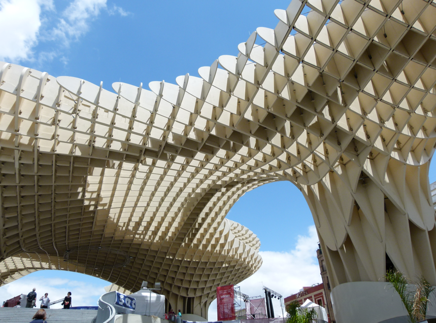 Een moderne, golvende houten constructie in Sevilla, Spanje, met ingewikkelde geometrische patronen onder een blauwe hemel.