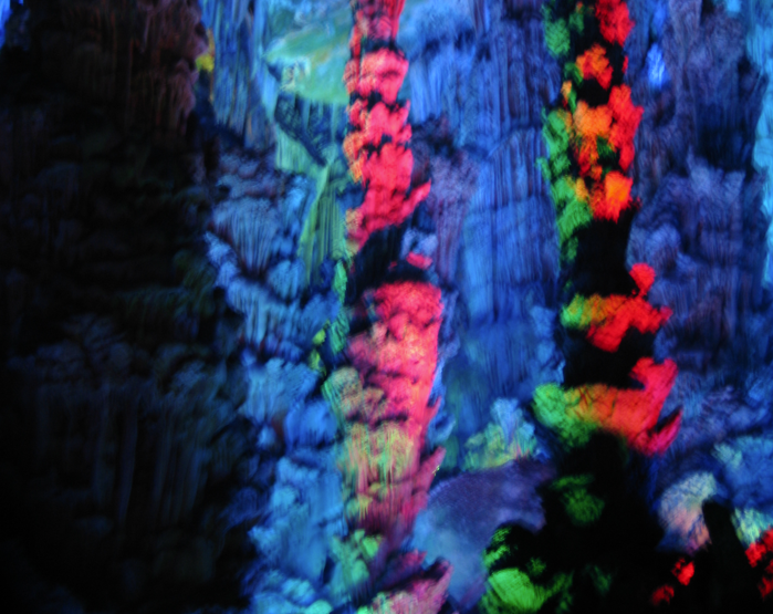 Kleurrijke grotformaties verlicht met blauwe, rode, oranje en groene lampen.