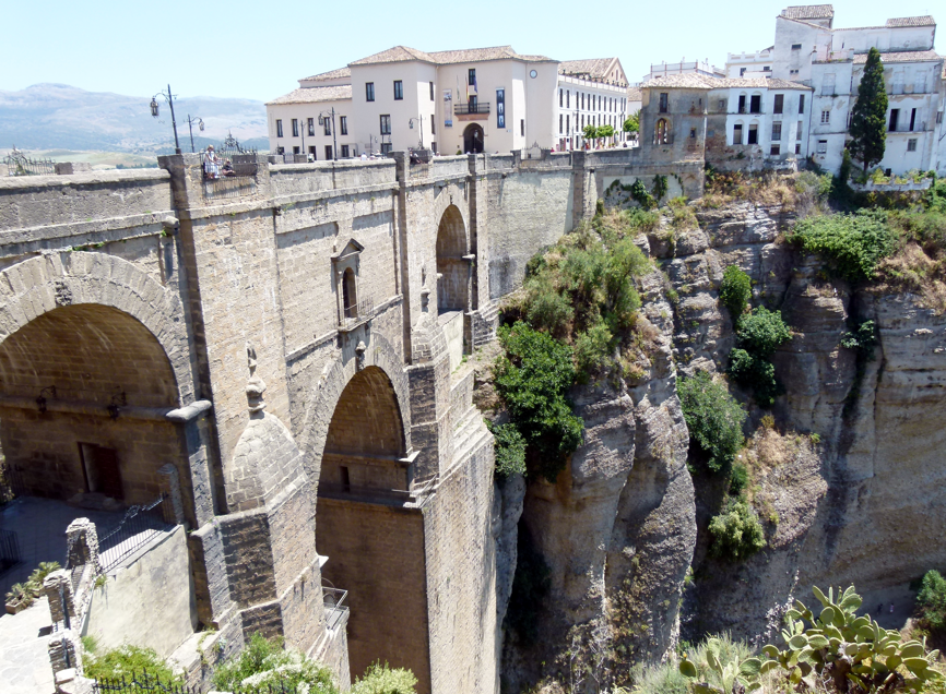 Stenen brug over een diepe kloof in Ronda, Spanje, met gebouwen op de achtergrond.