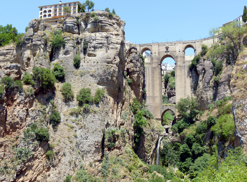 Stenen brug over een diepe kloof in Ronda, Spanje. Gebouwen bovenop kliffen, bogen, waterval.