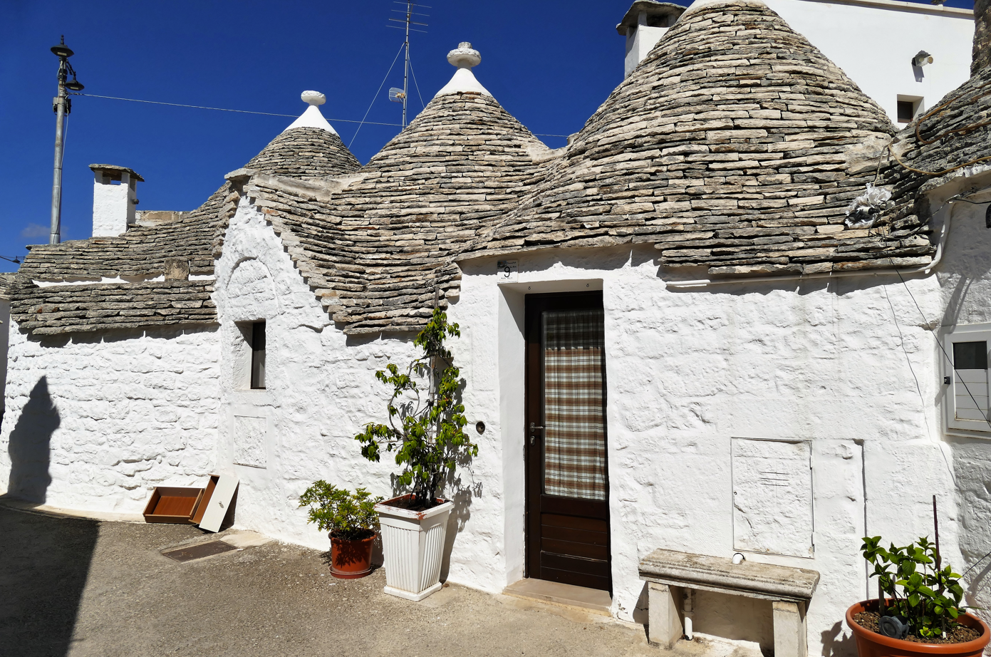 Witgekalkte trulli-huizen met kegelvormige stenen daken onder een helderblauwe hemel in Alberobello, Italië.