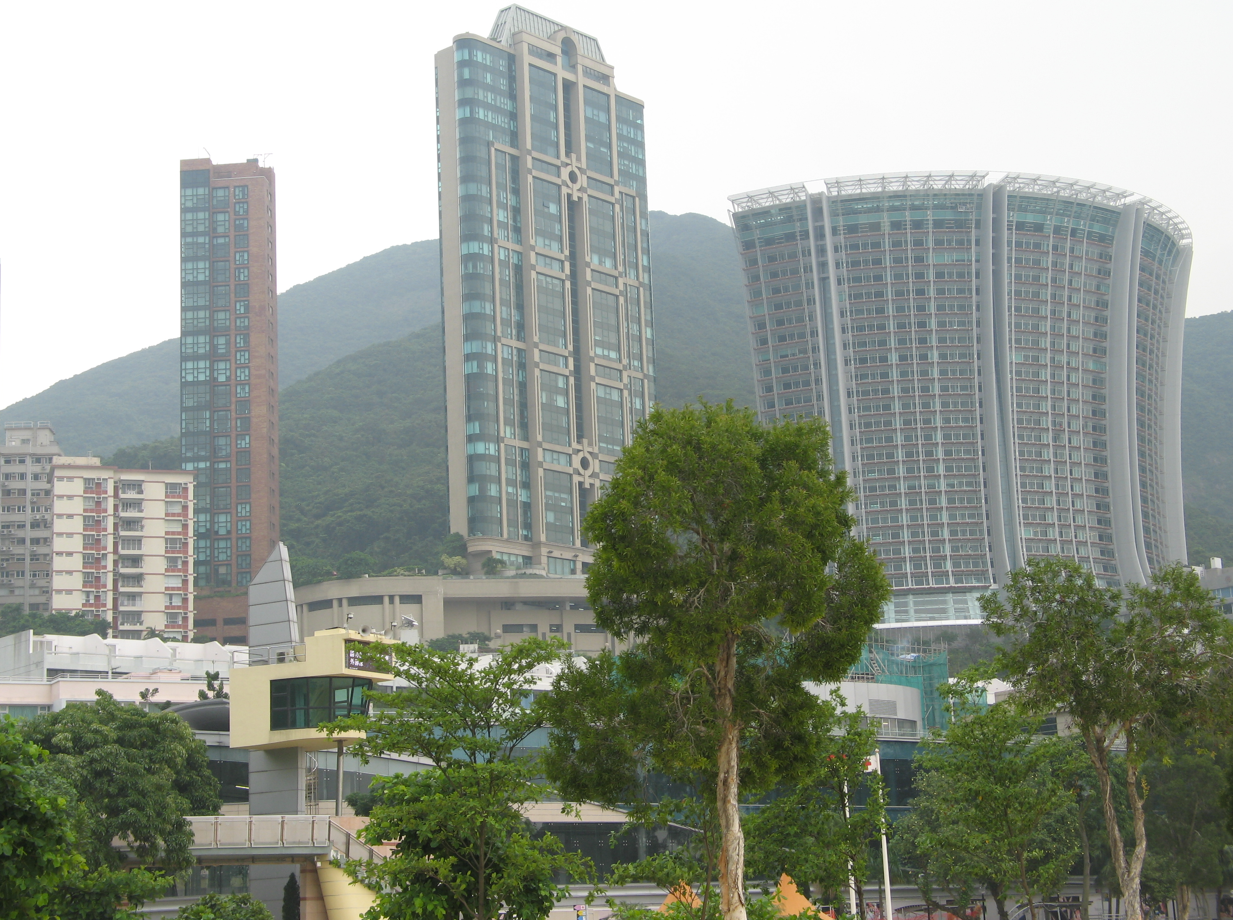 Stadsgezicht met moderne wolkenkrabbers en groene bomen tegen een heuvel in Hongkong.