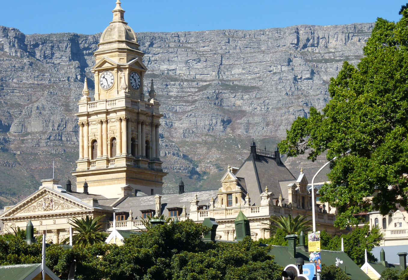 Klokkentoren met de Tafelberg op de achtergrond. Gebouwen op de voorgrond, zonnige dag.