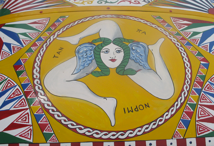 Het Siciliaanse Trinacria-symbool met drie benen, vleugels en een Gorgonenhoofd, omgeven door geometrische patronen.
