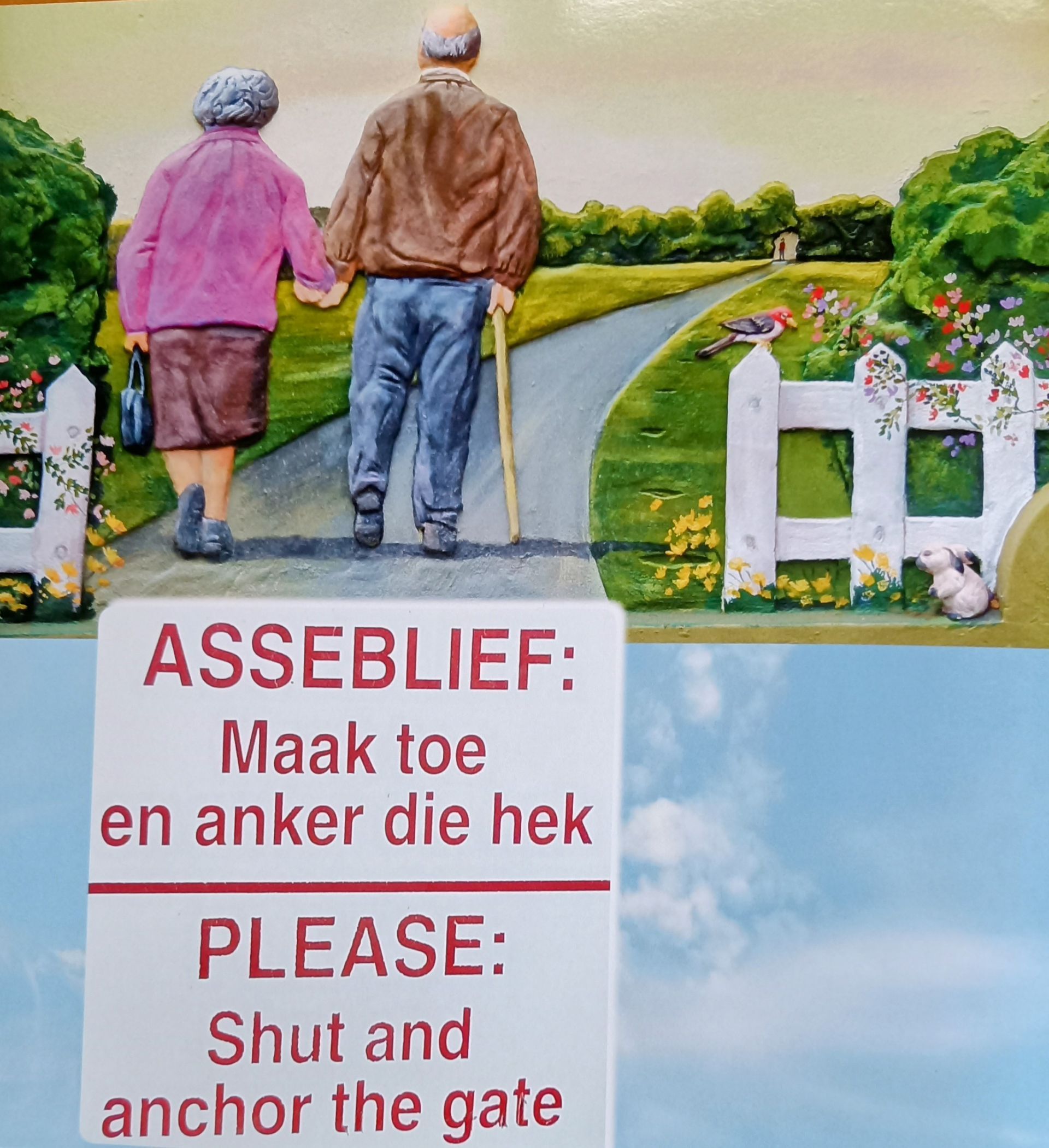 Een ouder echtpaar loopt, met een bordje waarop in het Engels en Afrikaans staat: 