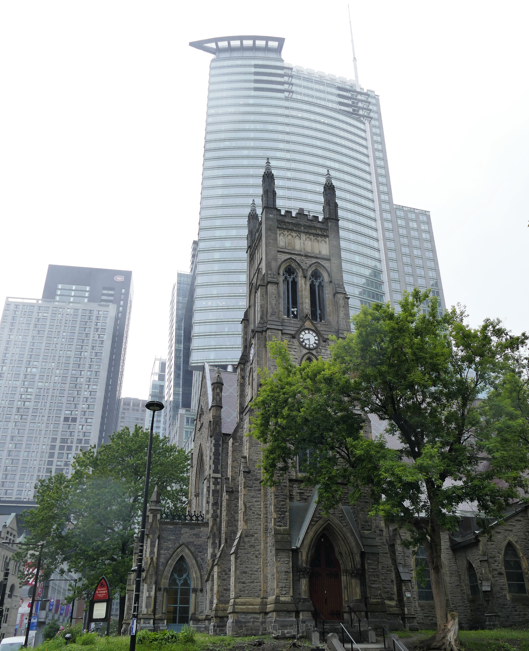 Een gotische kerk voor een moderne wolkenkrabber in Toronto, Canada, op een bewolkte dag.