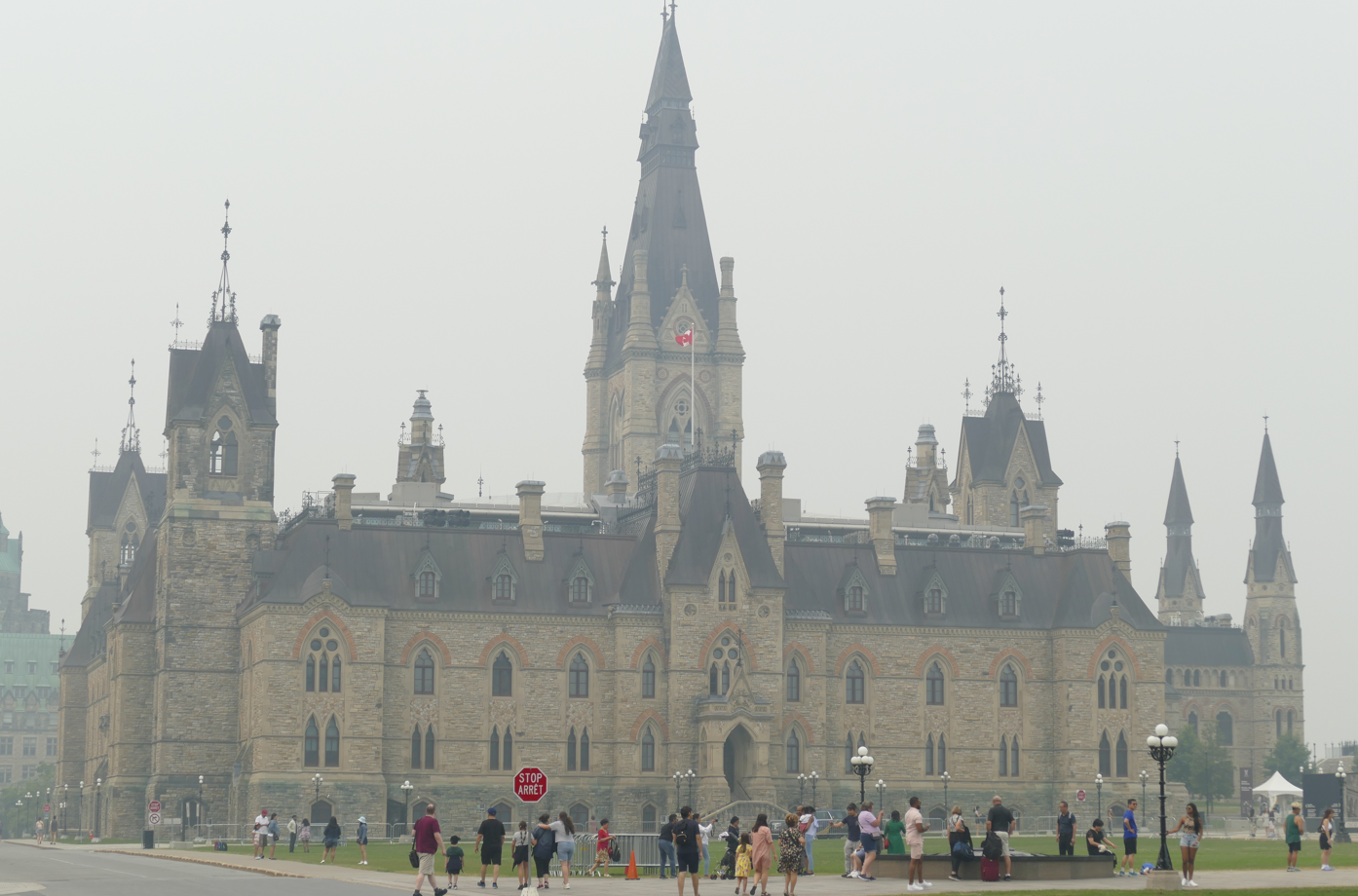 Het parlementsgebouw in Ottawa, Canada, op een mistige dag; mensen lopen op de voorgrond.