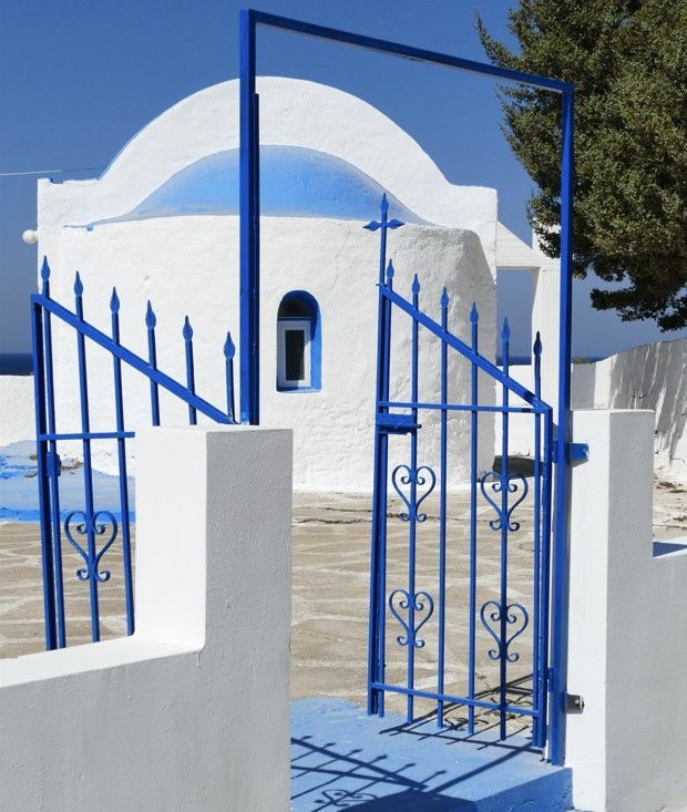 Blauw-witte Grieks-orthodoxe kerk met gewelfd dak en poort.