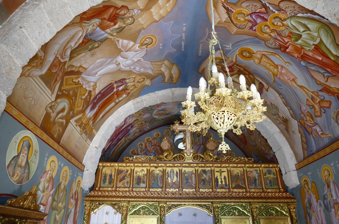In een kerk hangen sierlijke plafondfresco's en een altaar, met daarboven een gouden kroonluchter.