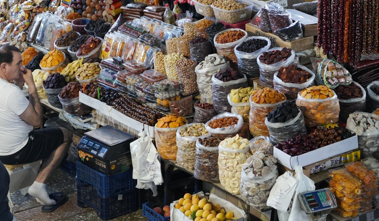 Een openluchtmarktkraam vol kleurrijke gedroogde vruchten, noten en specerijen in schalen en bakken.
