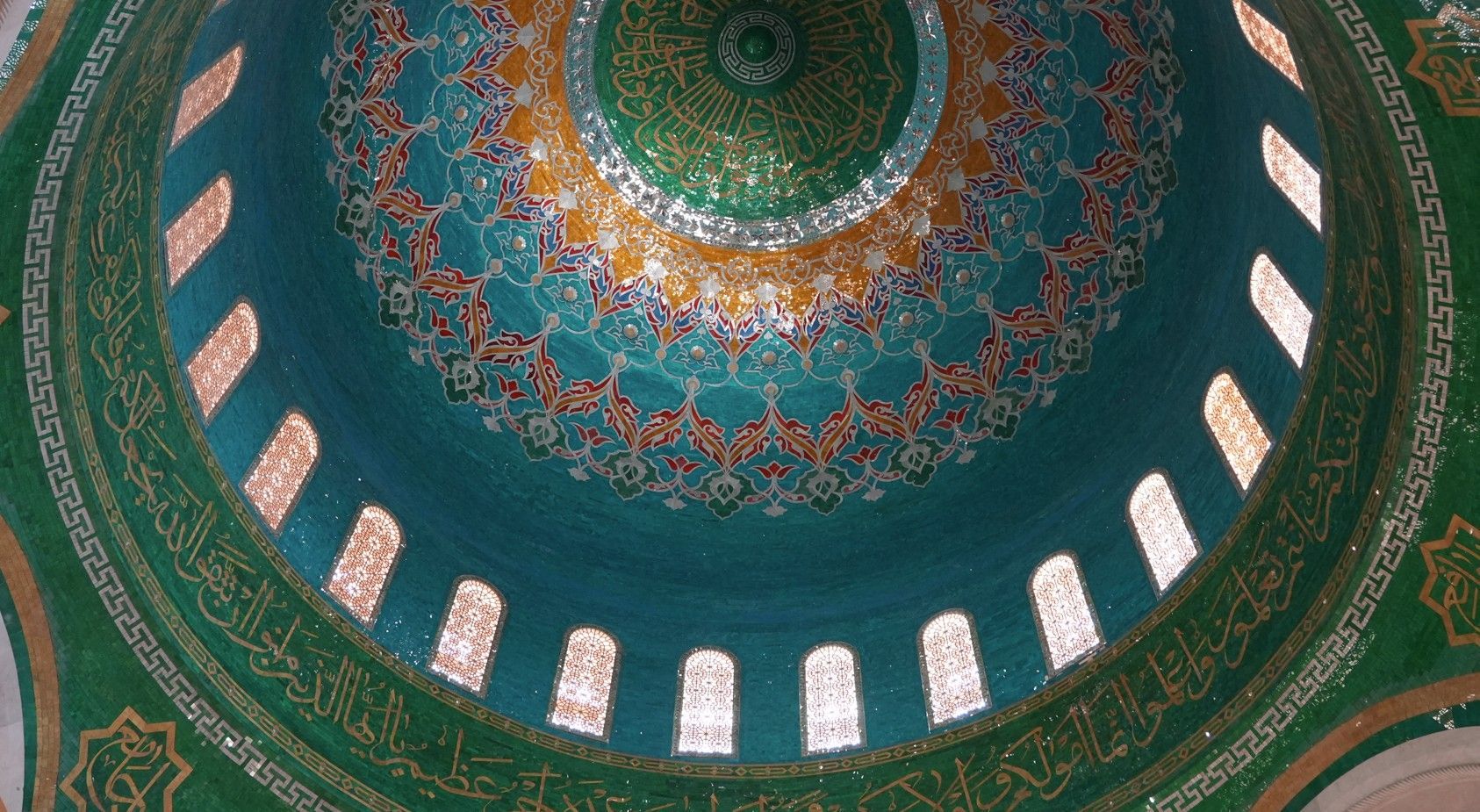 Het rijkversierde koepelplafond van de moskee is uitgevoerd in turquoise en goud. BAKOE
