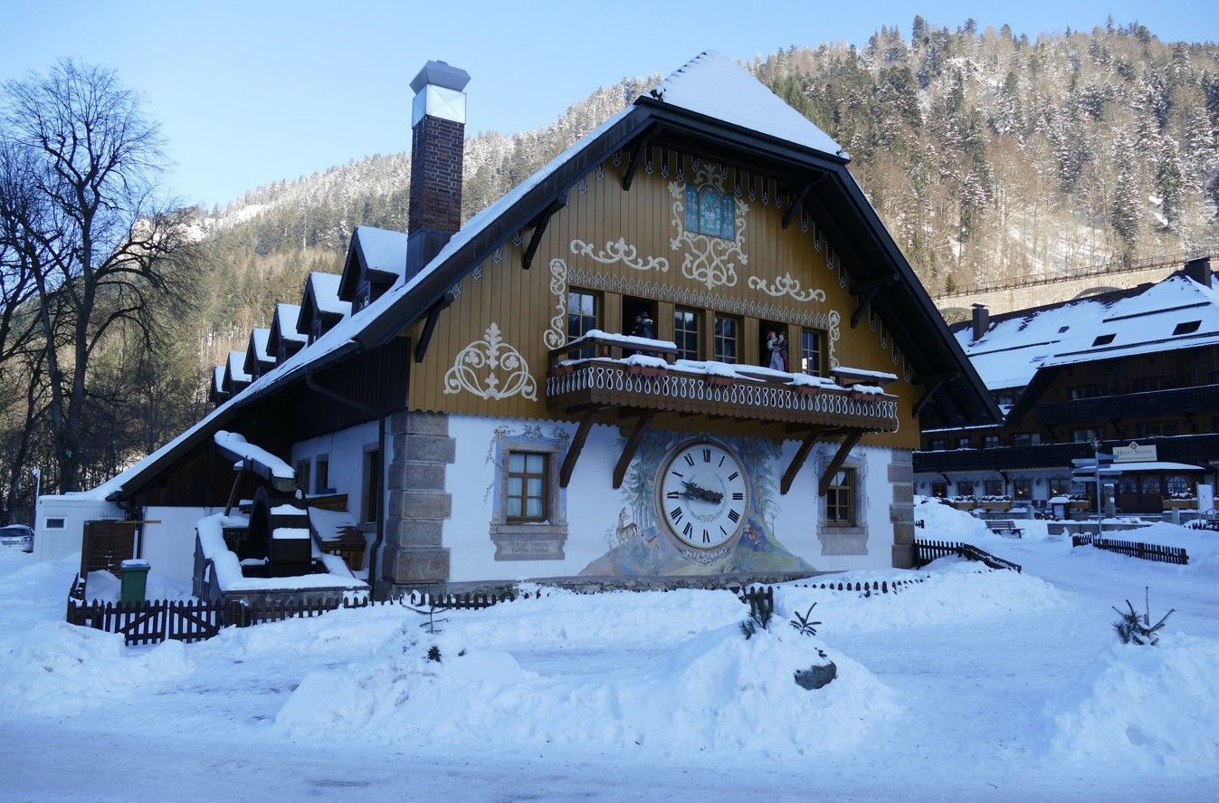 Een met sneeuw bedekt traditioneel huis met een grote klok, mogelijk in het Zwarte Woud, Duitsland.