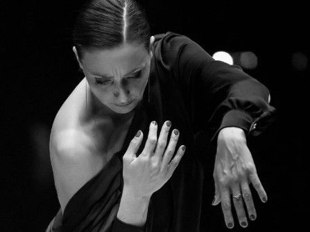 Flamencodanseres in beweging, armen omhoog, geconcentreerde uitdrukking. Zwart-wit.