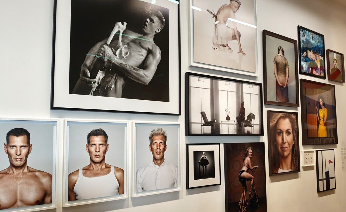 Galerijwand met ingelijste foto's van mensen en abstracte kunst.