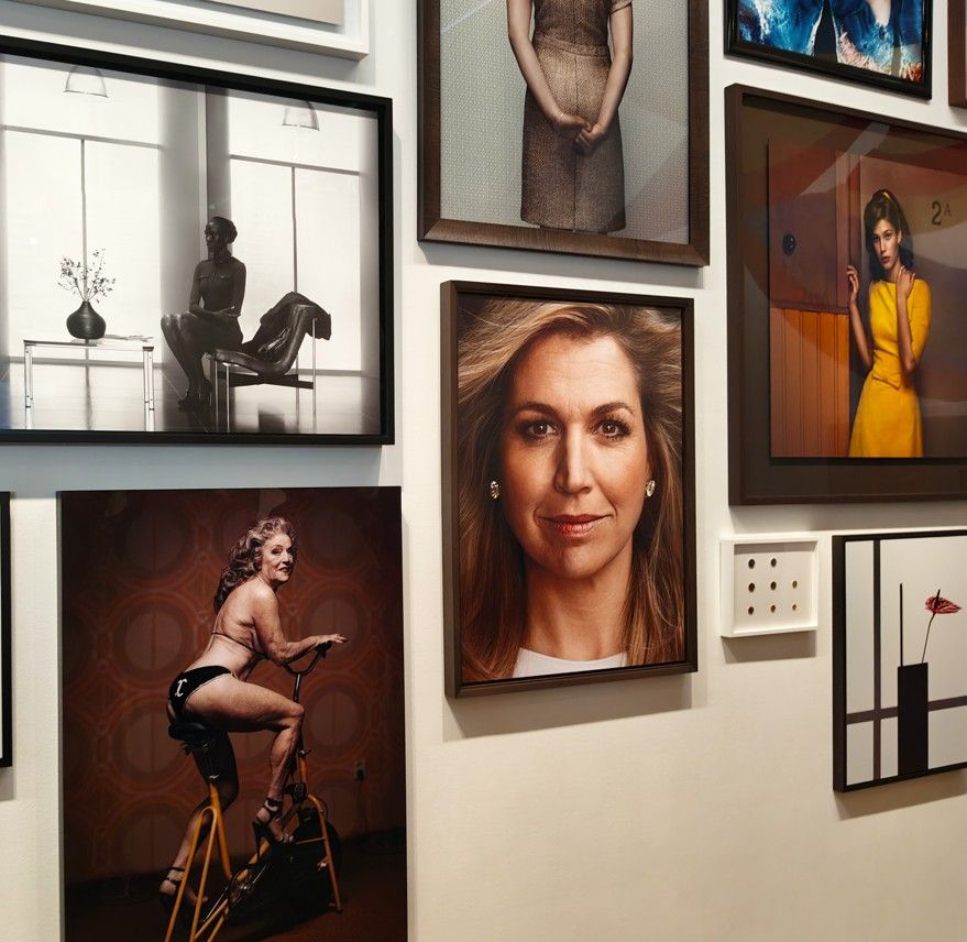 Een wand vol ingelijste foto's; diverse onderwerpen, waaronder portretten en geënsceneerde scènes.