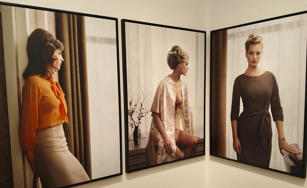 Aan de muur hangen drie ingelijste foto's. Vrouwen in retrokleding poseren in verschillende omgevingen met vintage mode.