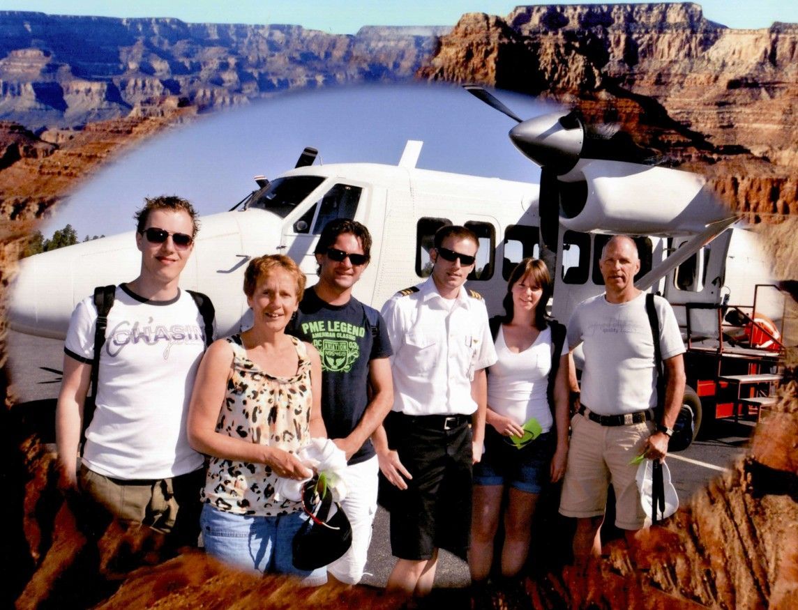 Een groep mensen poseert met een vliegtuig voor de Grand Canyon.