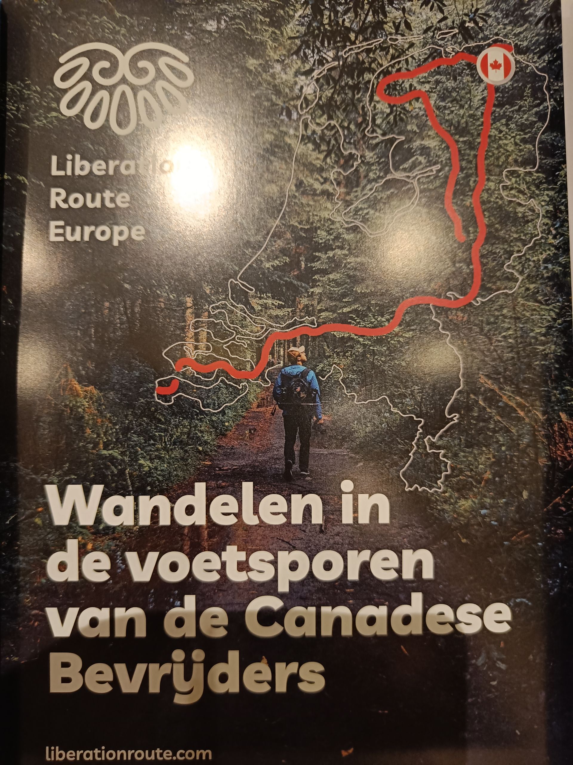 Brochure voor een Canadese bevrijdingsroute. Een persoon loopt over een pad; een kaart toont een route met een Canadese vlag.