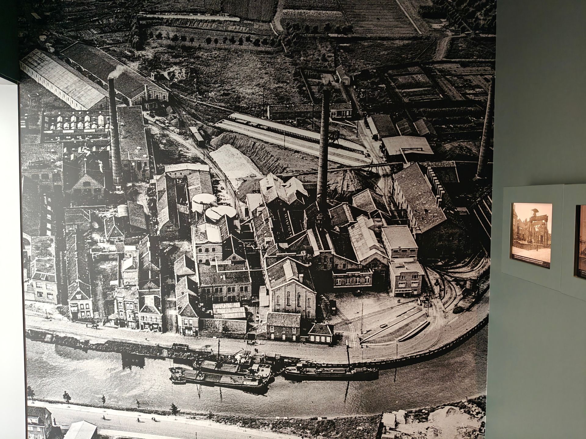 Zwart-wit luchtfoto van een drukke industriële haven met schepen, gebouwen en dokken.