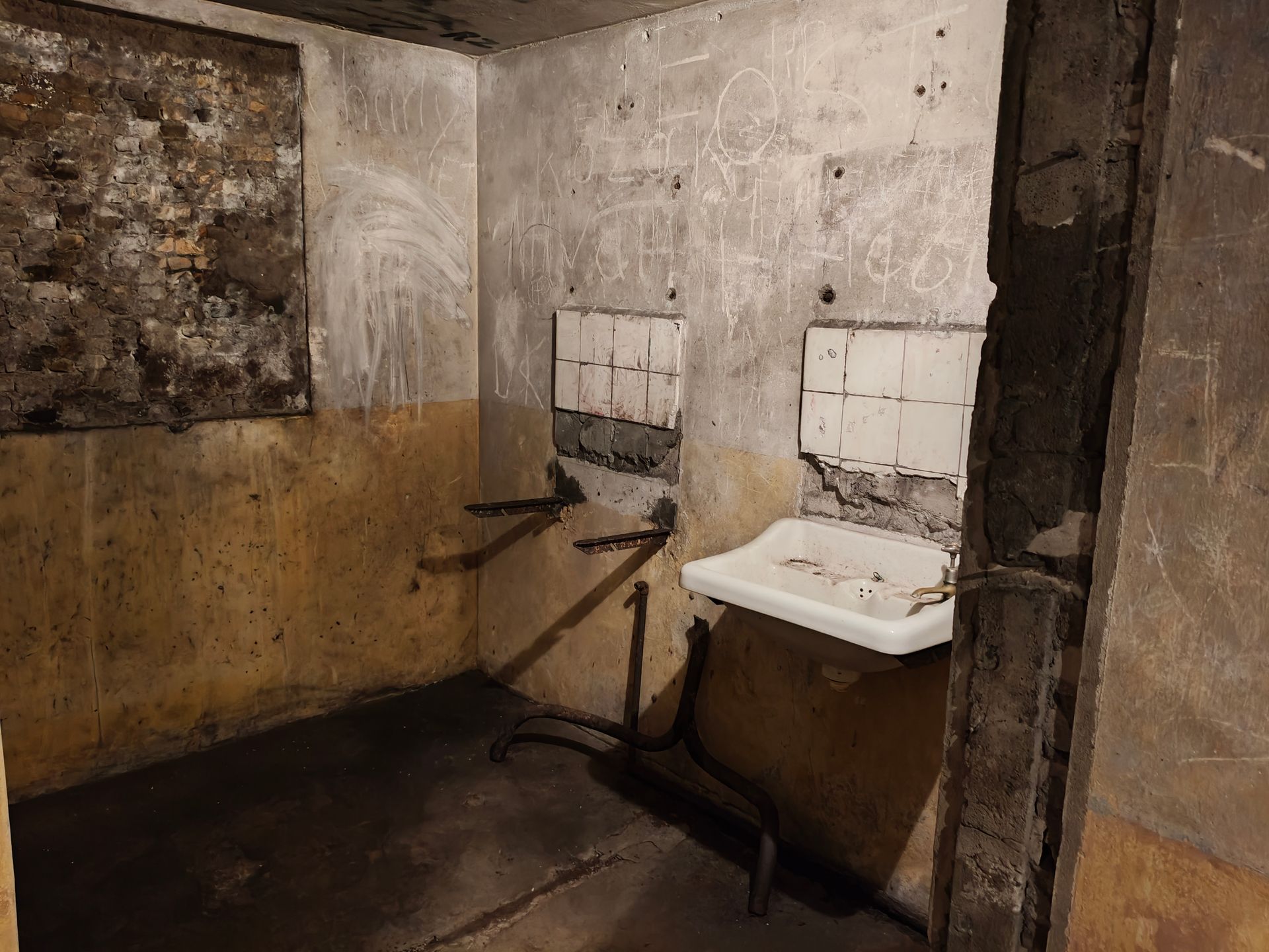 Een vervallen toiletruimte met vlekkerige muren en een kapotte wastafel in een smerige hoek.