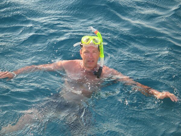 Persoon drijft in open water met een snorkelmasker en een felgroene snorkel.