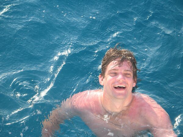 Lachende zwemmer in het blauwe oceaanwater, spetterend vlak onder het wateroppervlak.