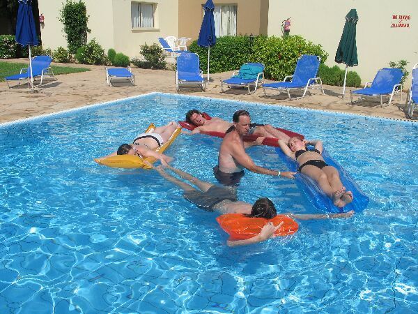 Mensen drijven samen in een zwembad en ontspannen op kleurrijke luchtbedden in een resort.