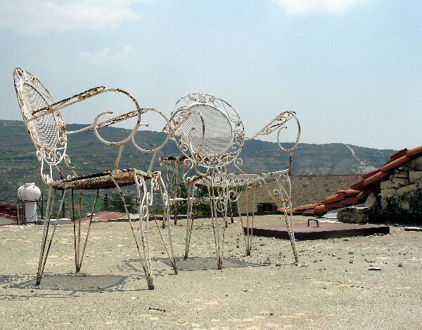 Draadsculptuur van abstracte dieren in een woestijnachtig buitenlandschap met heuvels op de achtergrond.