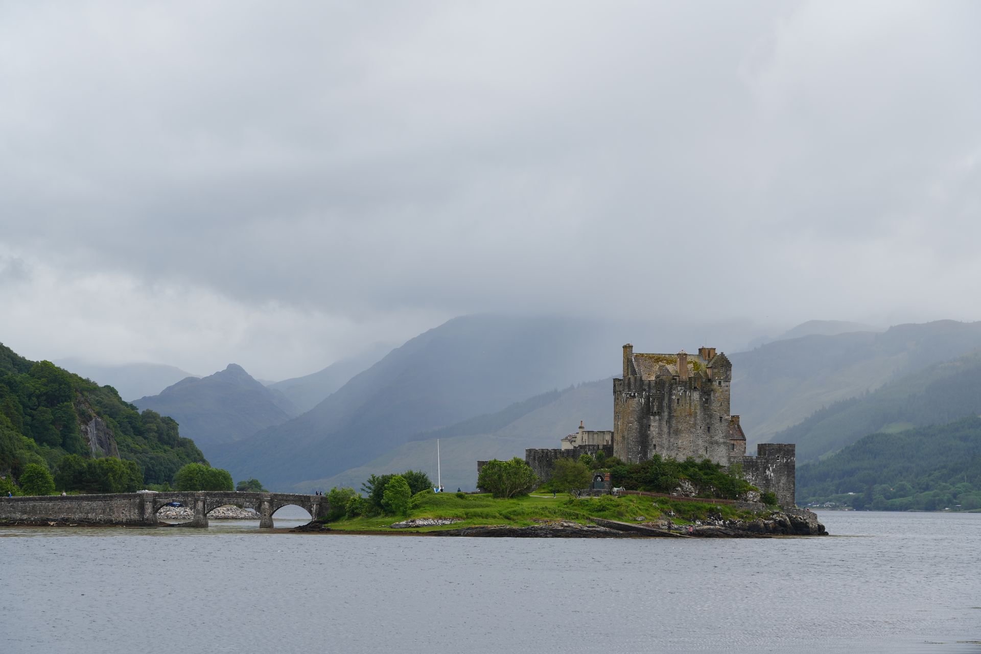 Kasteel Eilean Donan in Schotland, gelegen op een klein eiland. Een grijs stenen kasteel met een brug.