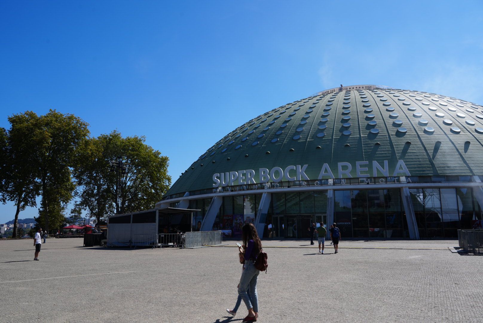 De buitenkant van de Super Bock Arena te Porto. Een groot koepelvormig gebouw onder een blauwe hemel.