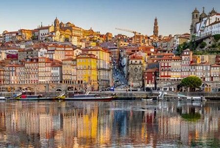 In Porto, Portugal, staan ​​kleurrijke gebouwen langs een rivier die in het water eronder weerspiegelt.