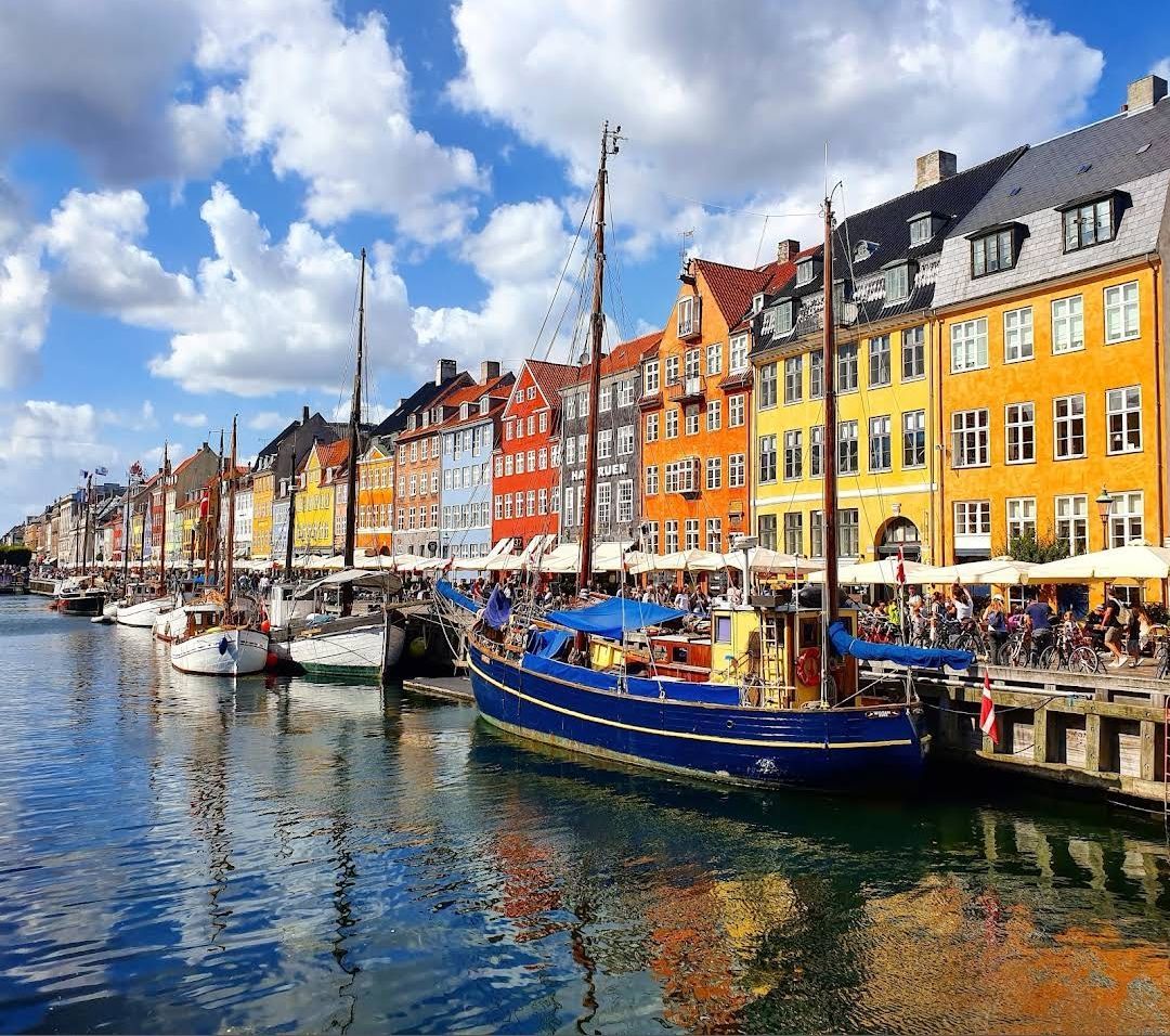 Kleurrijke gebouwen aan het water en boten langs een zonnig kanaal, waarschijnlijk Nyhavn, Kopenhagen.