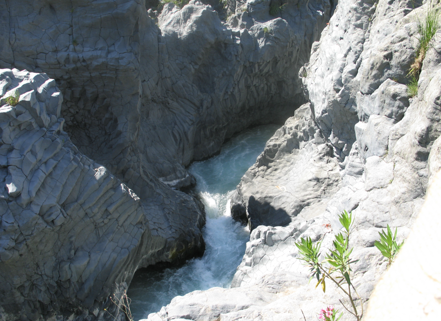 Een wildwaterrivier stroomt door een rotsachtige kloof met grijze rotswanden.