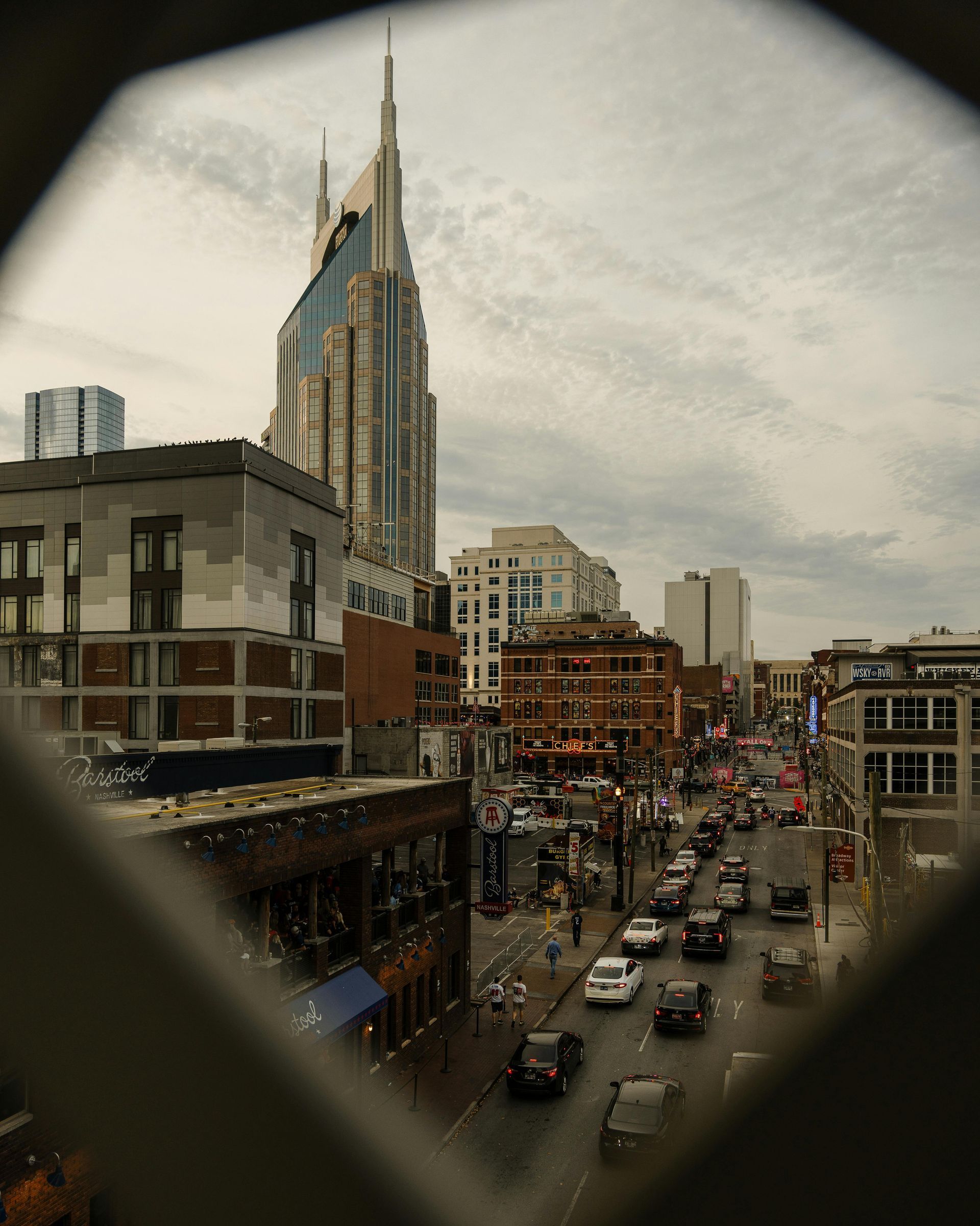 Stadsgezicht van Nashville, Tennessee, met een hoge wolkenkrabber en een drukke straat met auto's en gebouwen.