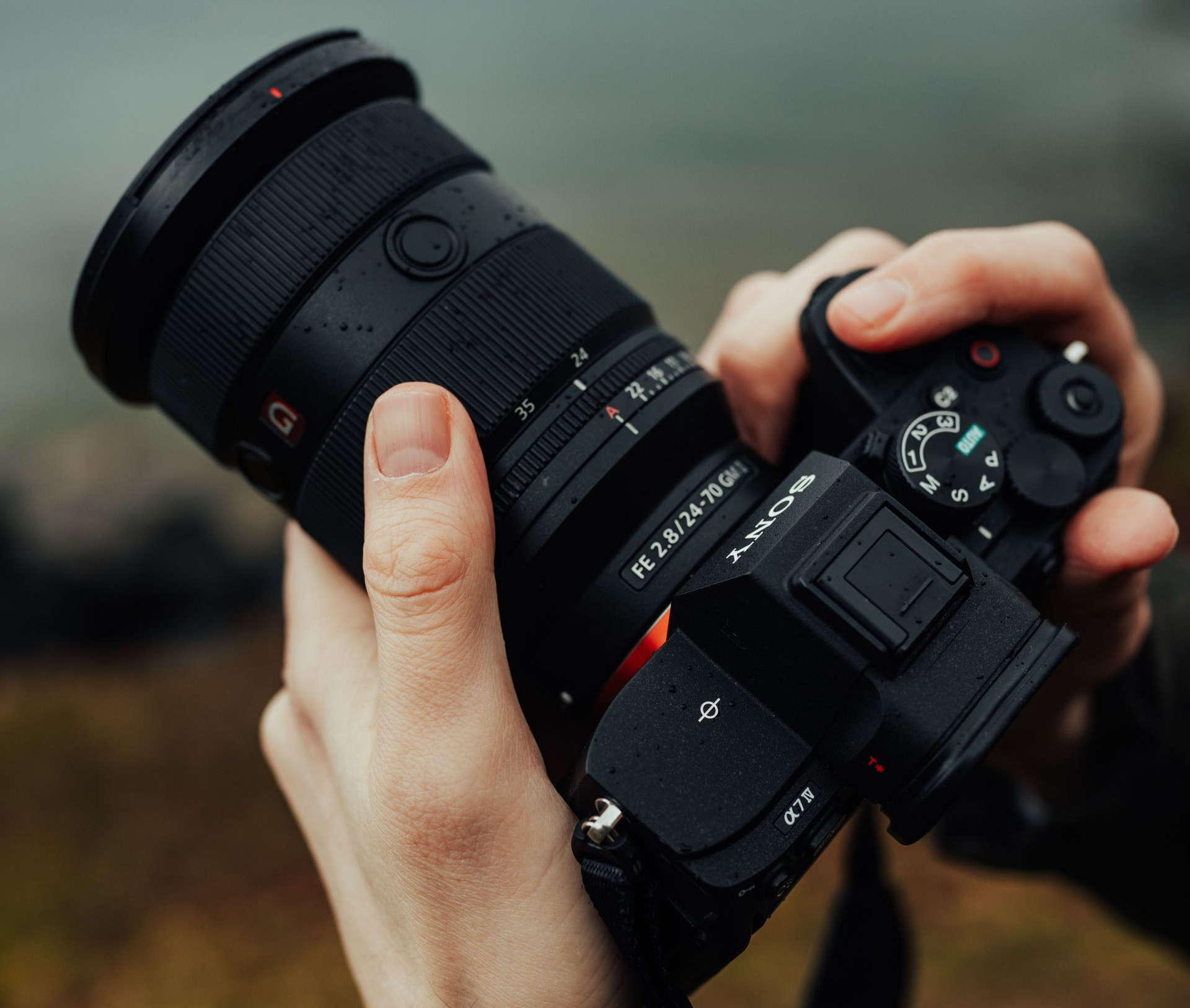 Handen die buiten een zwarte spiegelreflexcamera met een grote lens vasthouden.