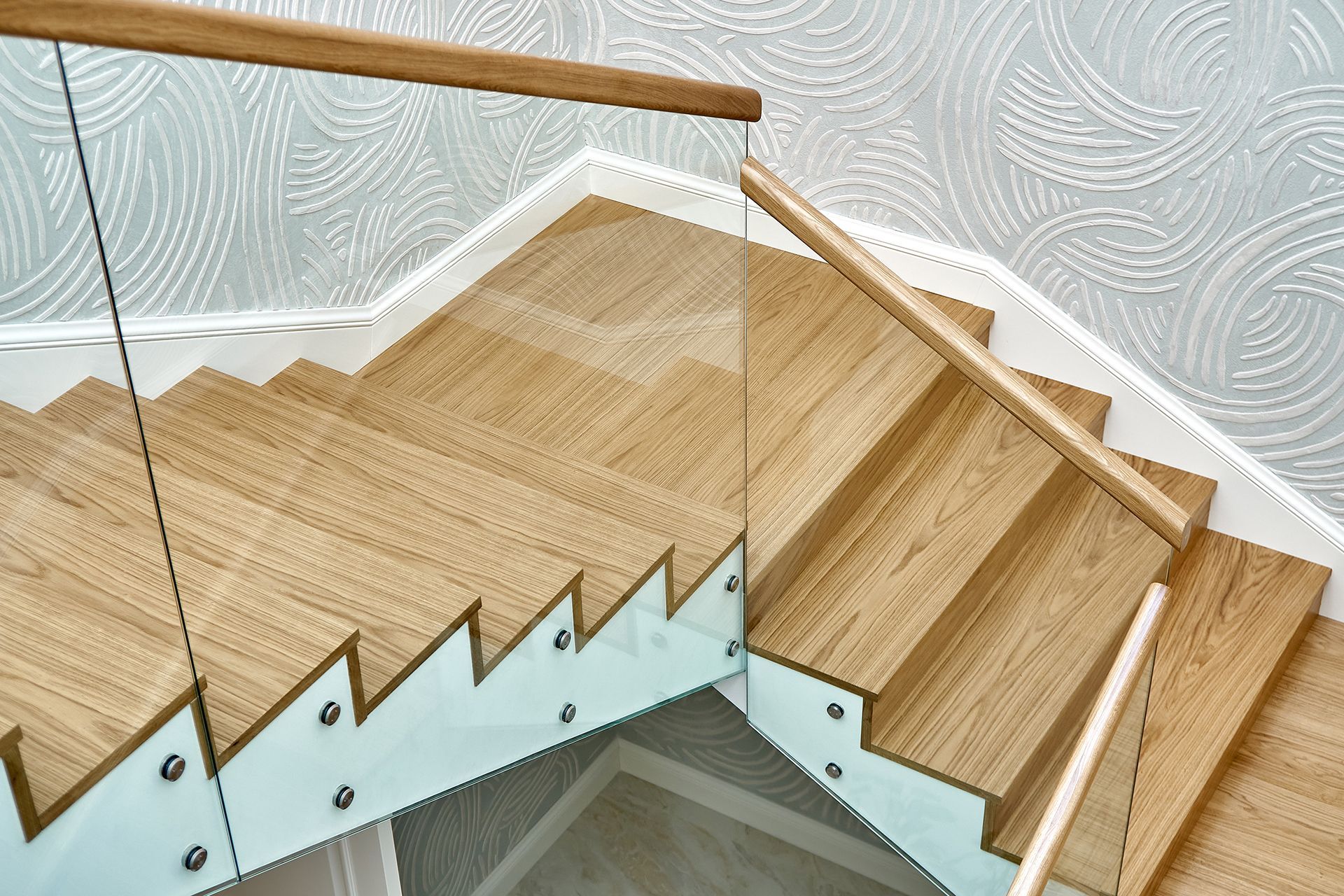 A wooden staircase with a glass railing and a wooden handrail