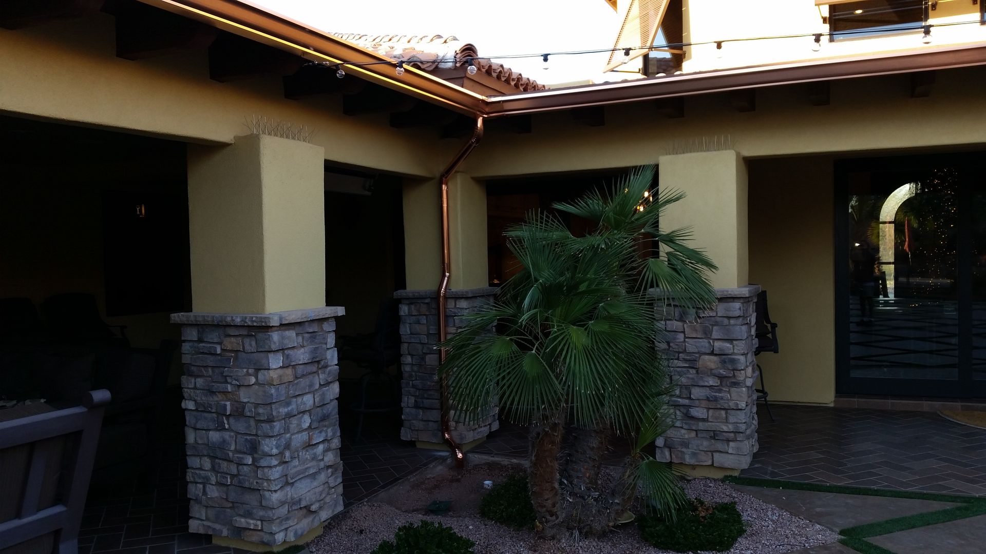 Installer securing a copper seamless gutter on an East Valley home.