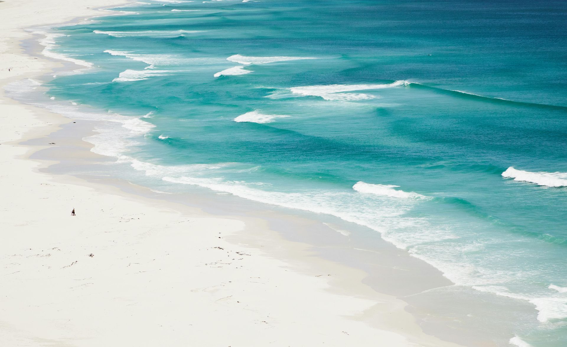 White sandy beach with turquoise water and gentle waves.