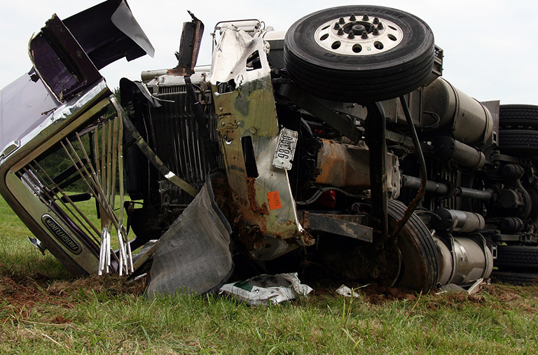 A truck that has crashed on its side in a field