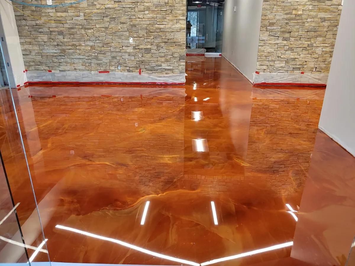 Shiny orange epoxy floor in a hallway with stone walls and white door frames