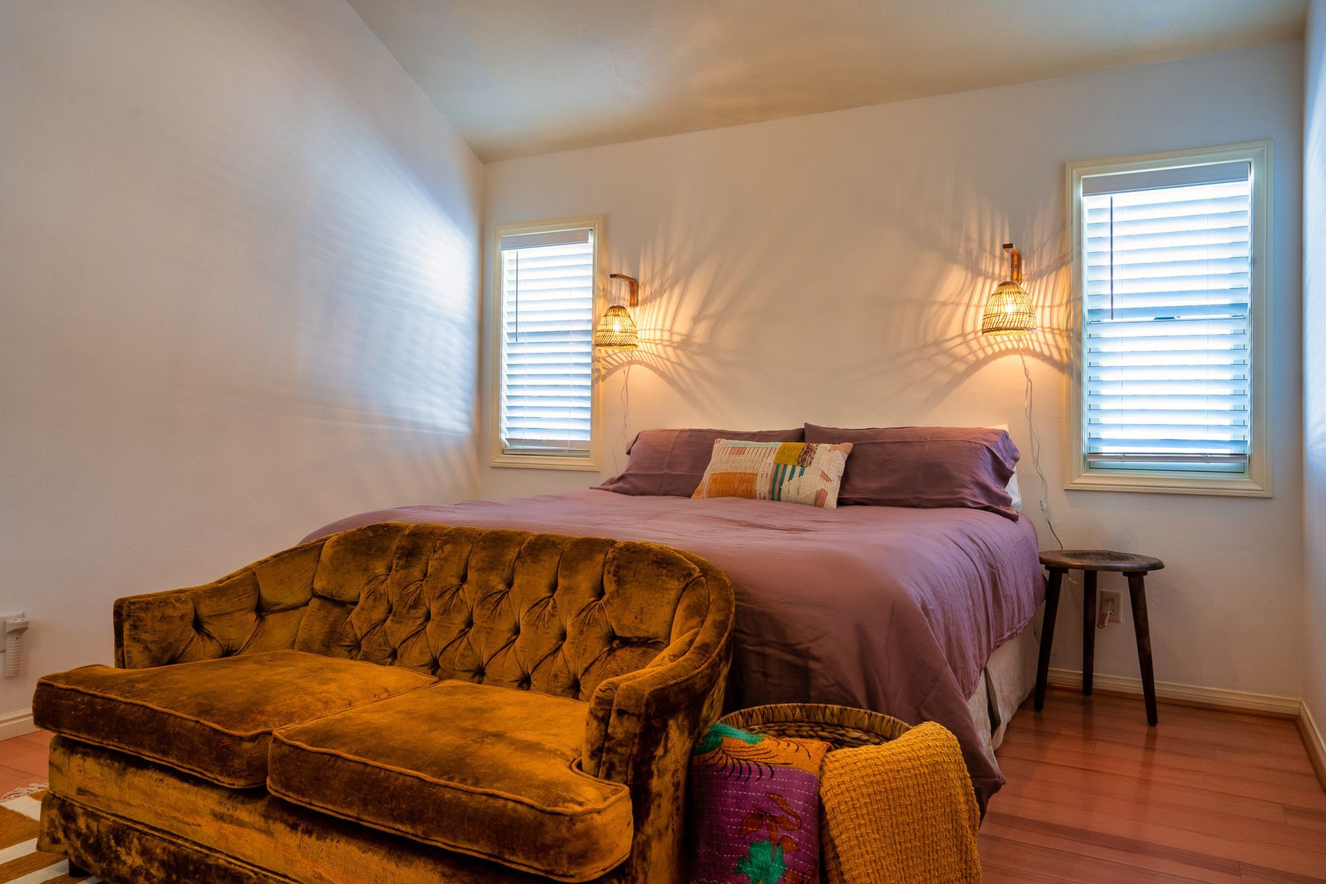 A bedroom with a bed , couch , and two windows.