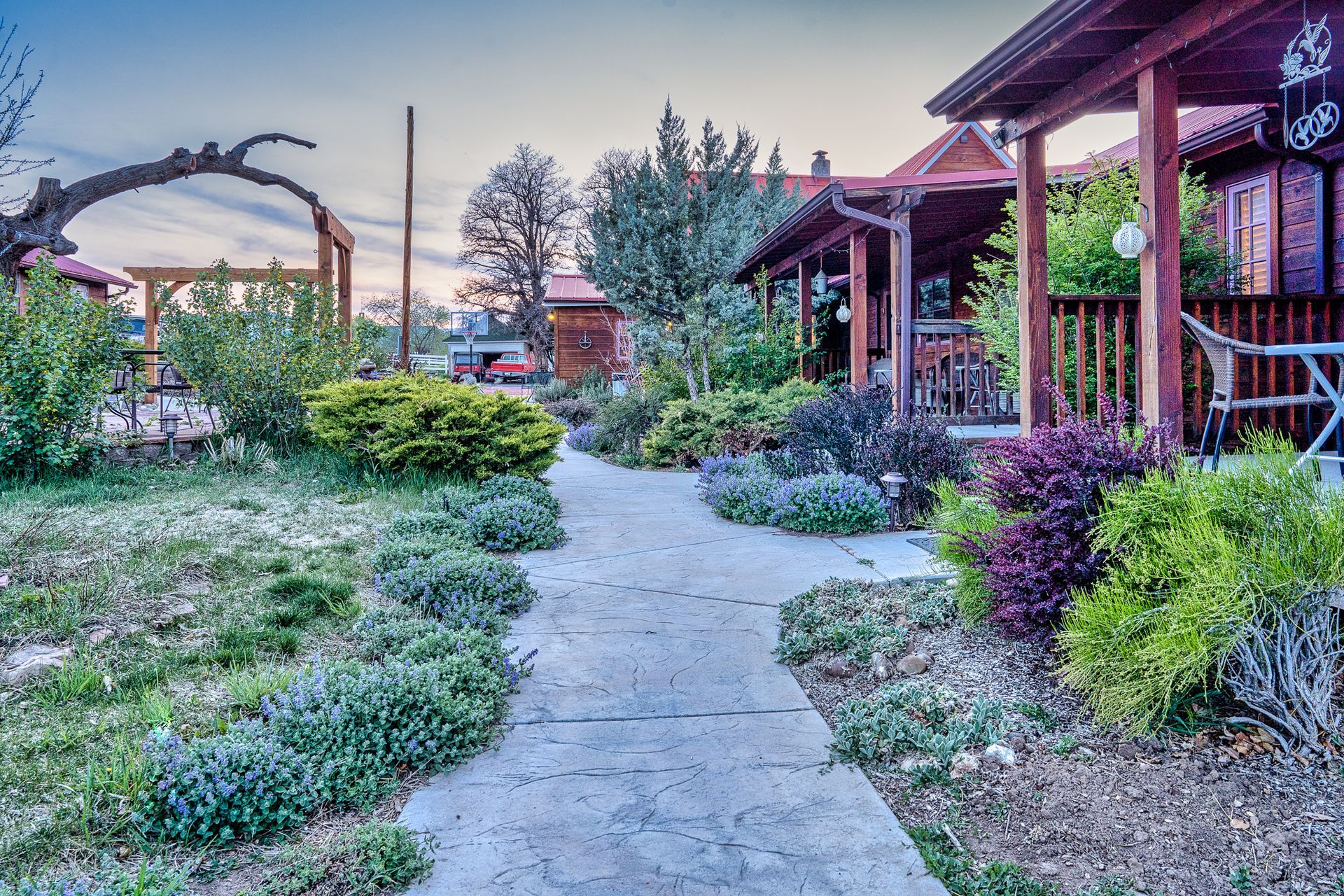 A concrete walkway leading to a house with a porch