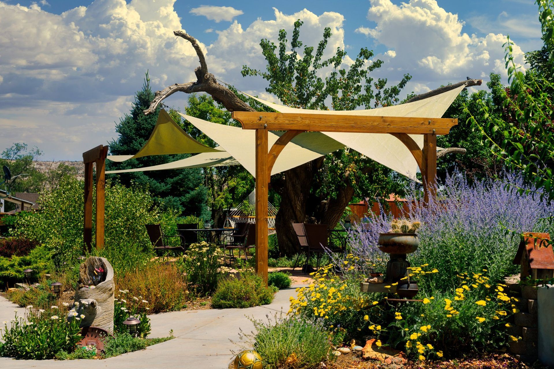 A garden with a wooden pergola and shade sails