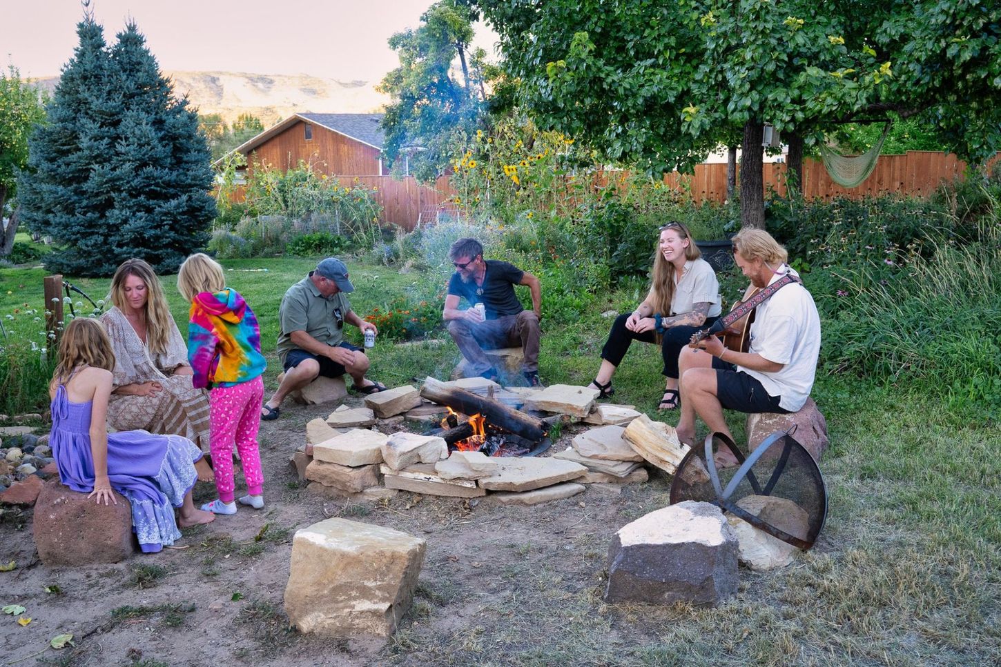 A group of people are sitting around a fire pit.